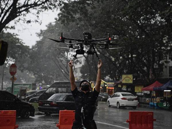 Pegawai Unit Dron Pasukan Gerakan Udara (PGU) PDRM Bukit Aman, Inspektor Nitas Camillus bersedia untuk menyambut pendaratan dron selepas membuat pemantauan udara di Bazar Ramadan Desa Pandan hari ini. - Foto Bernama