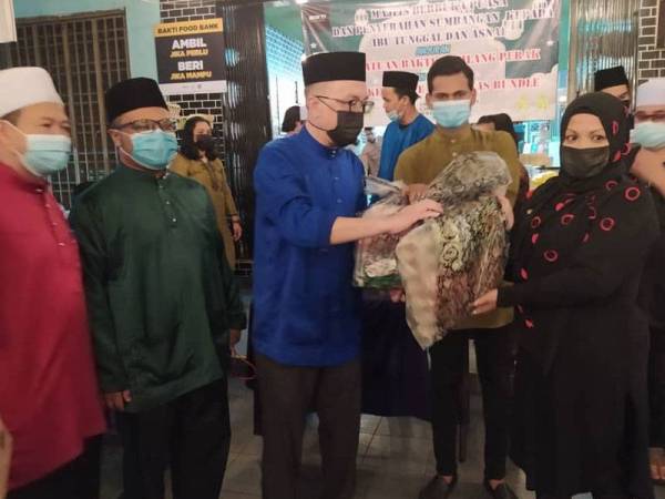 Aminuddin (tengah) menyampaikan sumbangan kepada penerima terpilih sambil diperhatikan Muhammad Khalish Nantha (dua dari kanan) pada Majlis Berbuka Puasa dan Penyerahan Sumbangan Kepada Ibu Tunggal dan Asnaf anjuran Persatuan Bakti Gemilang Perak di Jo Bakery Cafe, di sini pada Selasa.