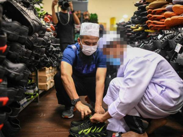 Ebit membantu remaja lelaki mencuba sebuah kasut sebelum ditempatkan di sebuah sekolah madrasah. - Foto: Facebook Ebit Lew