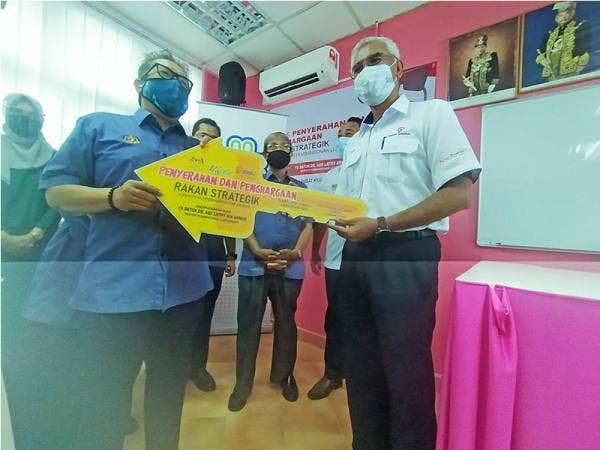 Dr Abdul Latiff menyerahkan replika kunci penghargaan kepada Pengurus Besar TNB Pulau Pinang/Kedah/Perlis, Ir Azmi Md Yusof ketika lawatan tapak projek Pusat Kegiatan Masyarakat Kuah Langkawi pada Jumaat.