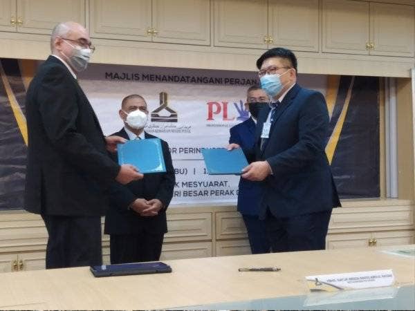 Saarani (dua dari kiri) menyaksikan pertukaran dokumen perjanjian di antara PKNP yang diwakili Redza Rafiq (kiri) dan Terence Lim di Bilik Mesyuarat, Pejabat Menteri Besar Perak, di sini pada Rabu.