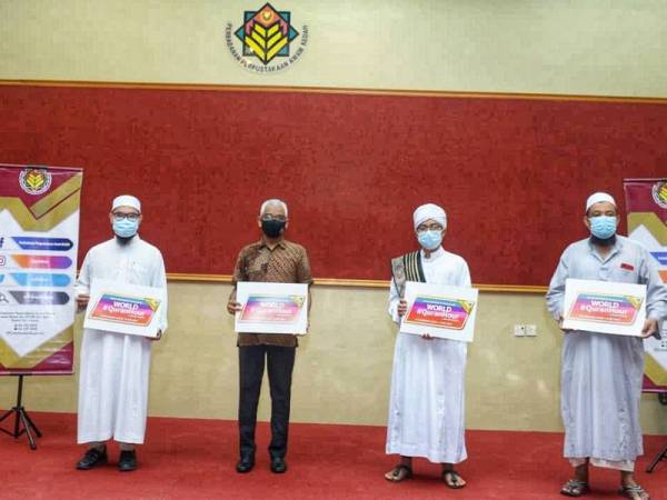 Shahizan Affandi (dua dari kiri) bergambar sambil memegang plakad promosi World #QuranHour di Perbadanan Perpustakaan Awam Kedah (PPAK), Alor Setar pada Khamis.