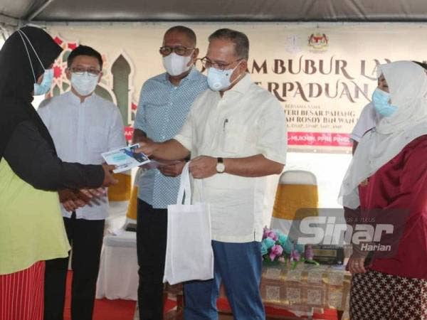 Wan Rosdy (dua dari kanan) menyampaikan sumbangan kepada penduduk sempena Program Bubur Lambuk Perpaduan di Projek Perumahan Rakyat (PPR) Pak Mahat, Kuantan pada Jumaat.
