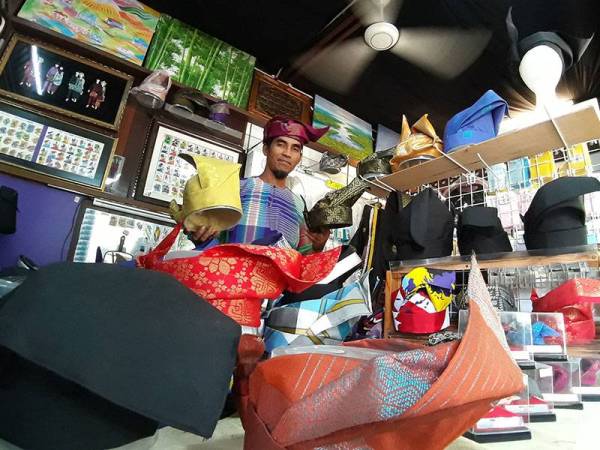 Mohd Iskandar bersama sebahagian daripada koleksi tanjak yang terdapat di kedainya di Perkampungan Kraf di Larkin, Johor Bahru.