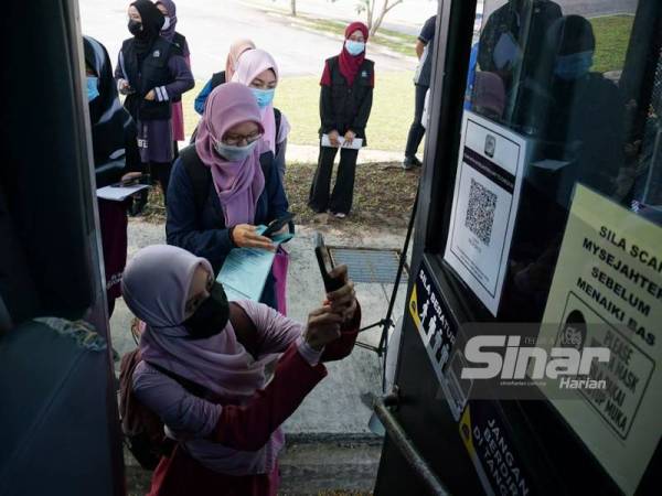 Mahasiswa USIM membuat imbasan QR Code MySejahtera sebelum menaiki bas yang membawa mereka pulang.