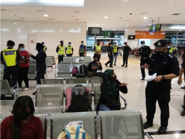 Mohamed Mokhsein (kanan) sedang menyemak borang rentas negeri salah seorang penumpang bas di TBS di Kuala Lumpur, pada Sabtu.