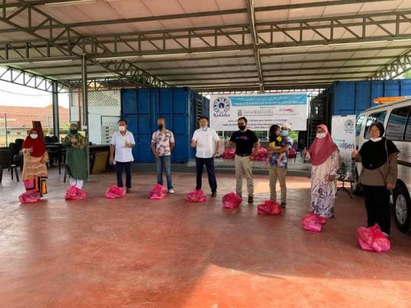 Penganjur menyumbangkan barangan keperluan dan wang tunai kepada penerima ketika program di Kampung Melayu Majidee, Johor Bahru pada Sabtu.