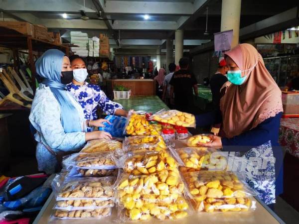 Suhana dan Noorsyakella melayan pelanggan yang datang membeli bahulu di gerai mereka di Pasar Am Beaufort.