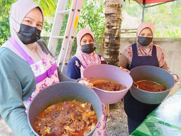 Zalina dan pekerjanya menunjukkan rendang ayam dan daging tempatan yang disediakan untuk dimakan bersama lemang.