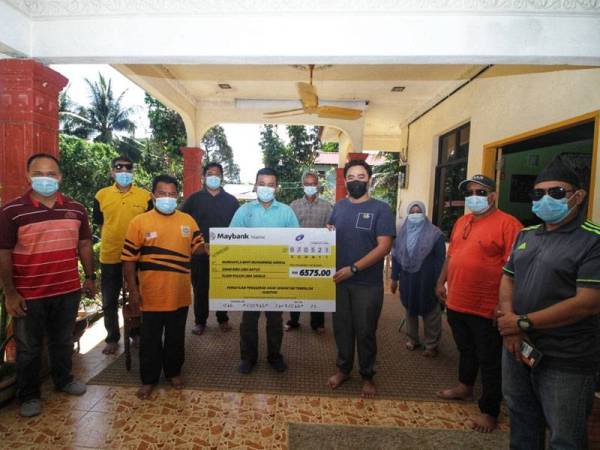 Amirul (depan, tiga dari kiri) menerima replika cek sumbangan yang disampaikan oleh Azizul (tengah) di Kampung Teluk Ira, Temerloh pada Ahad.