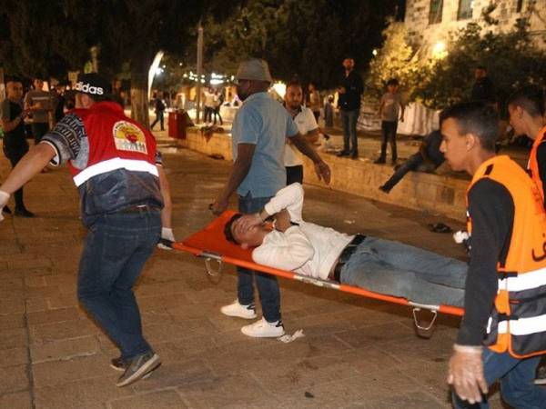 Seorang penunjuk perasaan Palestin cedera diusung oleh anggota-anggota perubatan dalam kejadian pertempuran dengan polis Israel di pekarangan Masjid Al-Aqsa, Baitulmaqdis baru-baru ini. - Foto AFP