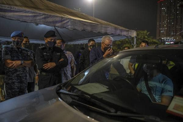 Menteri Kanan (Kluster Keselamatan) Datuk Seri Ismail Sabri Yaakob bertanyakan sesuatu kepada pemandu yang melintasi Sekatan Jalan Raya (SJR) Tol USJ pada Lawatan dan Penyampaian Sumbangan Raya kepada Petugas SJR malam tadi. -Foto Bernama