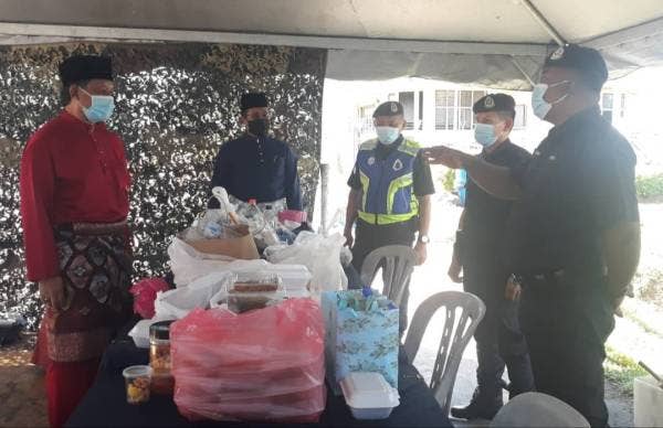 Dzowahir (kiri) beramah mesra bersama anggota keselamatan di SJR Tol Alor Setar Utara selepas menyerahkan juadah hari raya pada Khamis.