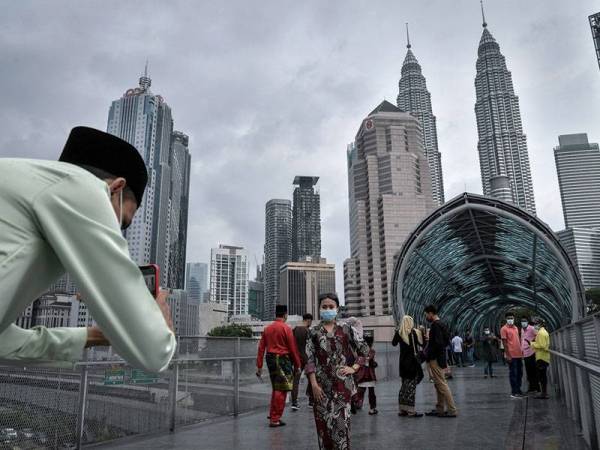 Warga kota mengambil kesempatan merakamkan kenangan sempena Aidilfitri berlatarkan menara berkembar Petronas selepas aktiviti merentas negeri dan daerah serta aktiviti ziarah hari raya tidak dibenarkan berikutan pelaksanaan Perintah Kawalan Pergerakan (PKP) 3.0 di seluruh negara ketika tinjauan di Pintasan Saloma hari ini.