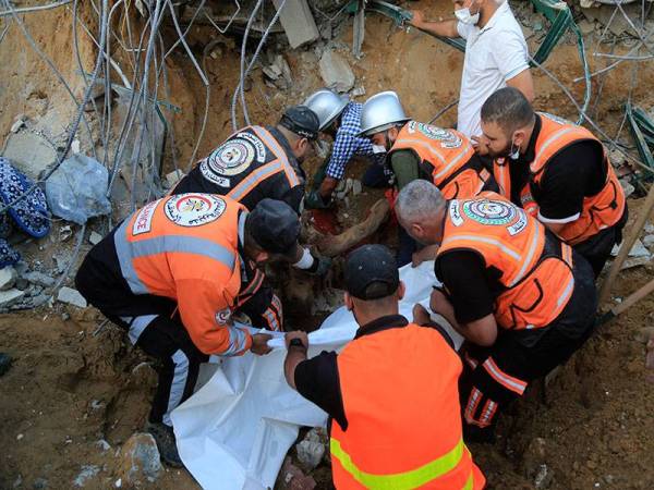 Pasukan paramedik Palestin mengeluarkan mayat mangsa yang ditemui di bawah runtuhan sebuah rumah yang musnah akibat kempen pengeboman rejim Zionis di utara Genting Gaza.