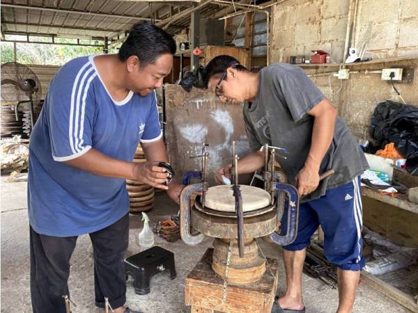 Mokhtar (kiri) menunjukkan proses pemasangan kulit kambing yang menjadi bahan utama dalam pembuatan kompang. - Foto Bernama 