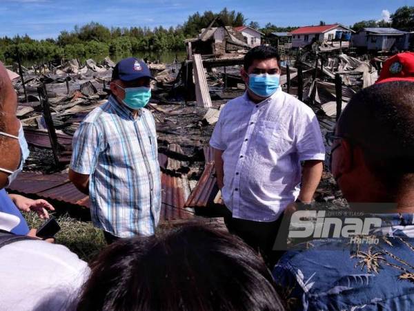 Shahelmey (kanan) dan Arifin (kiri) hadir meninjau lokasi kebakaran di Kampung Meruntum, Putatan pada Ahad.