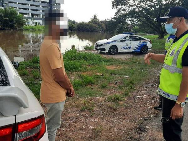 Ahmad Shukri (kanan) berkata sesuatu kepada lelaki yang dikenakan kompaun kerana merentas daerah dari Jitra ke Alor Setar ketika ditahan di Jalan Limbong Kapal pada Ahad. - Foto ihsan polis