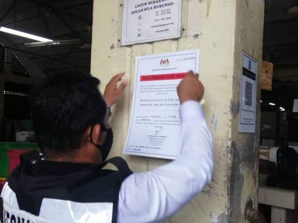 Pegawai kesihatan melekatkan notis arahan penutupan Pasar Awam Jelutong.