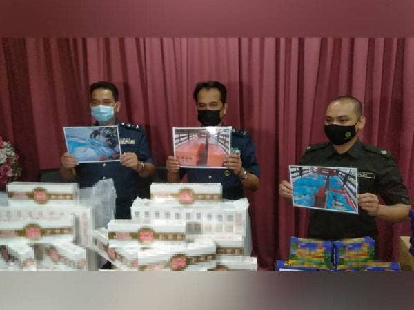 Sazali (tengah) menunjukkan rokok yang cuba diseludup dalam timbunan ikan di Kompleks Sultan Abu Bakar.