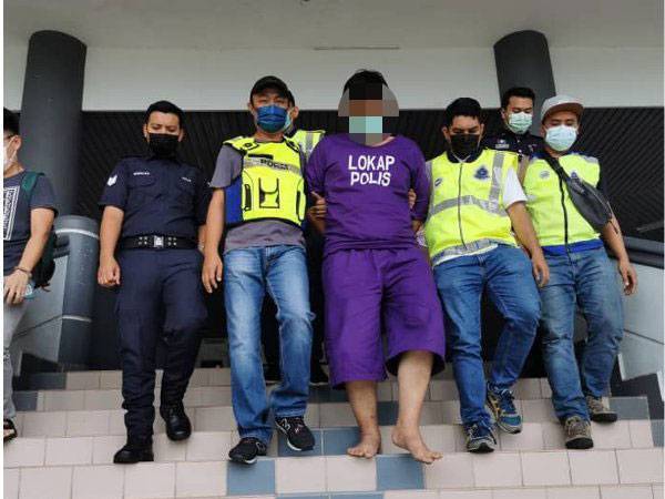 Suspek (tengah) diiringi anggota polis keluar dari Mahkamah Majistret Ayer Keroh di sini pada 14 Mei lalu.

