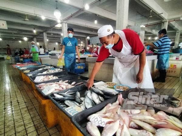 Suiad sedang menyusun ikan jualannya di Pasar Besar di sini pada Jumaat.