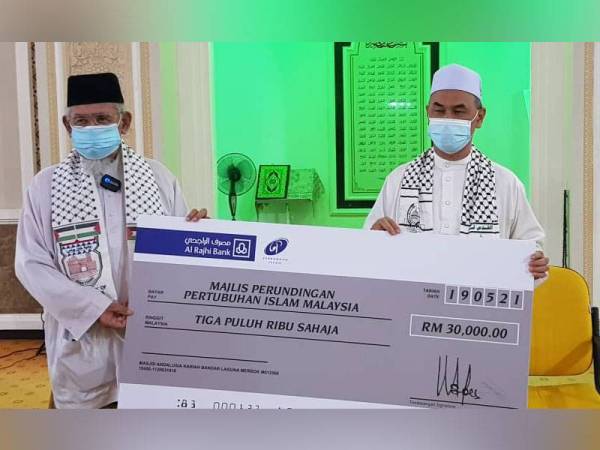 Pengerusi dan Imam Masjid Andalusia Bandar Laguna Merbok, Burhanudin Wahab (kanan) menyerahkan replika cek bernilai RM30,000 kepada Mohd Azmi pada Jumaat.