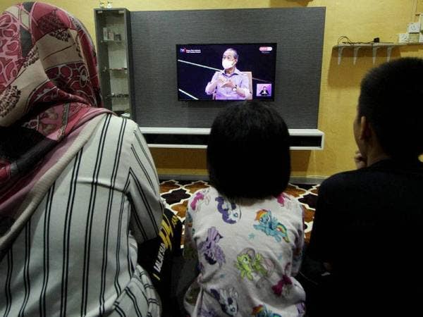 Zuazianirda Baharudin, 34, bersama anaknya Muhammad Irfan Mustaqim, 11, dan Nur Jannah Irsalina, 7, menonton Bicara Khas Eksklusif bersama Perdana Menteri Tan Sri Muhyiddin Yassin yang disiarkan secara langsung menerusi stesen televisyen tempatan di rumahnya di Pekan Razaki Ipoh hari ini.