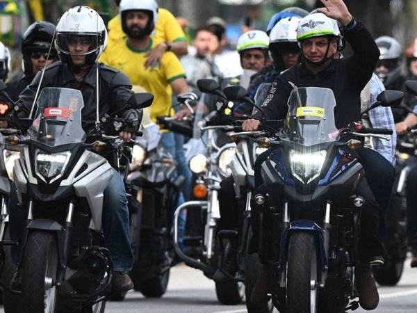 Bolsonaro (kanan) menunggang motosikal ketika mengetuai perarakan di Rio de Janeiro pada Ahad. - Foto: Agensi