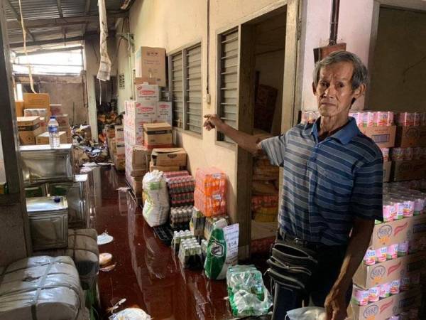 Ang Koh Hwa (kanan) menunjukkan kawasan belakang stornya yang terlibat dalam kebakaran tersebut.