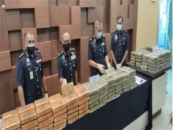 Mohd Roze (dua dari kiri) menunjukkan ketulan ganja yang dirampas dalam serbuan di Changlun dan Bukit Kayu Hitam pada Sabtu lalu.