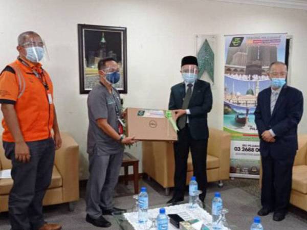 Ahmad Ruzman (tengah) memberikan sumbangan komputer riba kepada Dr Shahabuddin.