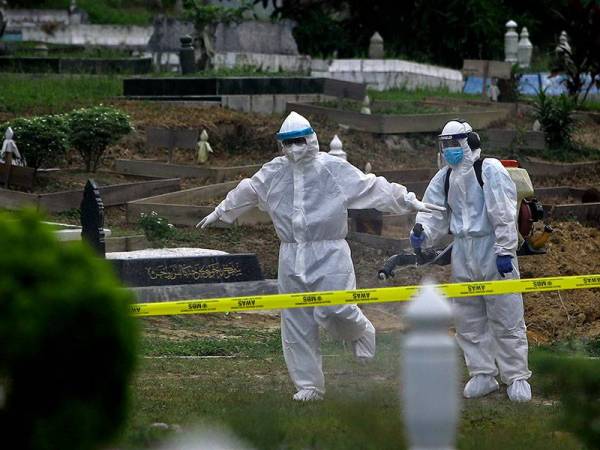 Seorang petugas KKM melakukan semburan sanitasi kepada seorang pasukan Tajhiz JHEAINS selepas selesai menyempurnakan urusan pengebumian jenazah pesakit COVID-19 di Makam Tuan Haji Said, pada Selasa. - Foto Bernama
