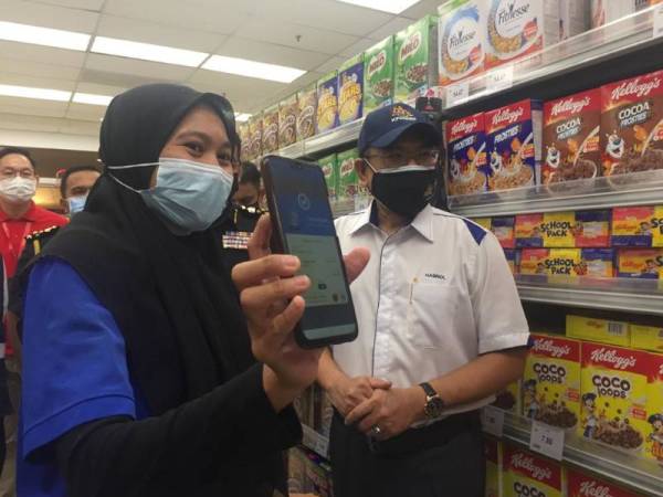 Hasnol (kanan) ketika meminta salah seorang pengunjung menunjukkan aplikasi MySejahtera bagi mengenalpasti tempoh masa yang digunakan.