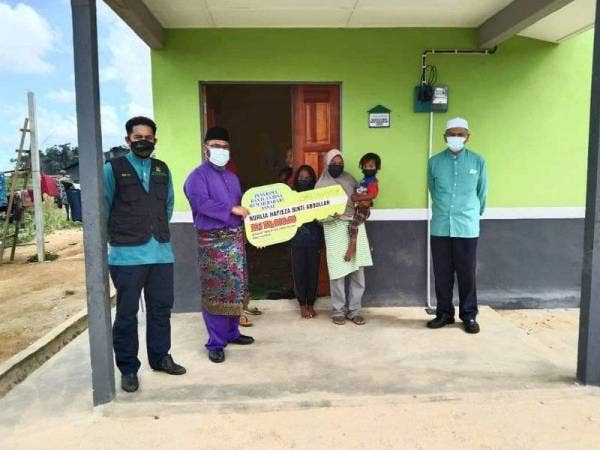 Asmadi (dua dari kiri) menyerahkan replika kunci rumah kepada salah seorang penerima bantuan bina rumah baharu MUIP kepada Nurlia Hafieza di Kampung Api Larat, Mukim Bebar, Pekan pada Khamis.