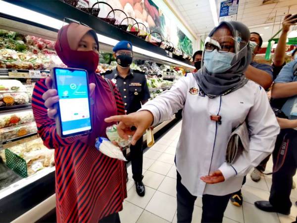 Ain Arjuna (kanan) menyemak aplikasi MySejahtera seorang pelanggan.