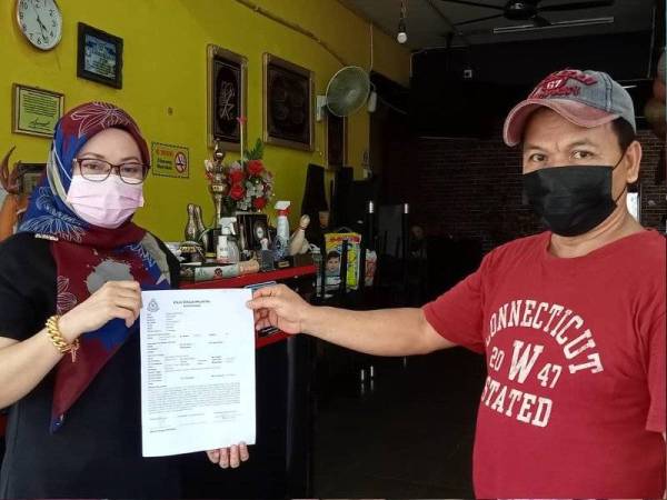 Azizan (kiri) menunjukkan laporan polis berikutan tabung derma untuk pembinaan masjid yang diletakkan di restorannya di Pusat Perniagaan Taman Saujana, Johor Bahru dilarikan pada Jumaat.