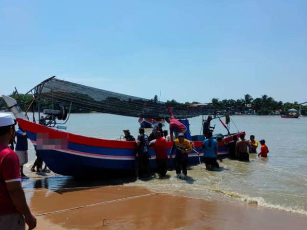 Bot nelayan yang terbalik berjaya ditarik ke tepi pantai selepas dipukul ombak besar dalam kejadian di Sungai Kuala Muda di sini pada petang Sabtu..