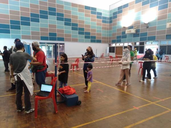 Orang ramai menunggu giliran bagi menjalani ujian saringan Covid-19 percuma di DUN Pelabuhan Klang pada Ahad.
