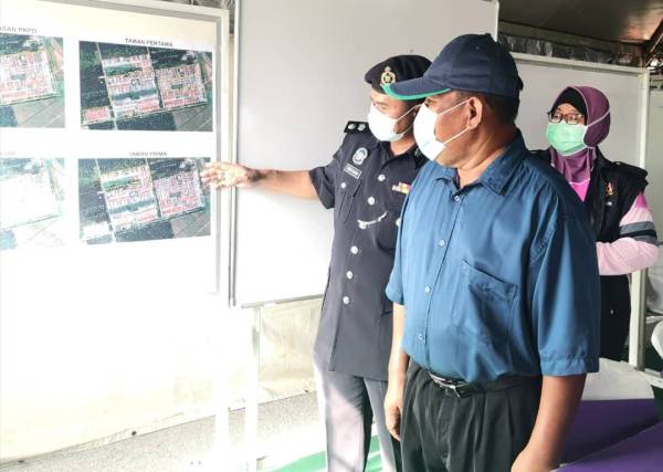 Agus Salim (kiri) menunjukkan pelan lokasi taman yang dikenakan PKPD kepada Ahli Dewan Undangan Negeri (ADUN) Sabak, Ahmad Mustain Othman (kanan) di Pusat Kawalan Operasi Bencana Taman Pertama di Sabak Bernam pada Ahad.