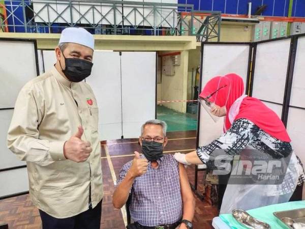 Dr Izani (kiri) bersama salah seorang penerima vaksin menunjukkan tanda sokongan di PPV Dewan Majlis Daerah Ketereh, Kota Bharu pada Ahad.
