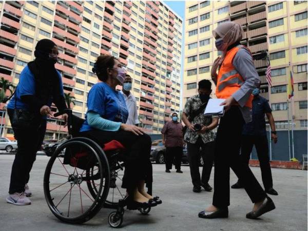 Rina (kanan) bersama Ras Adiba (dua, kiri) ketika hadir memberi bantuan serta membuat tinjauan di kawasan Program Perumahan Rakyat (PPR) Sri Sarawak sempena 'Total Lockdown' fasa pertama, pada Selasa.