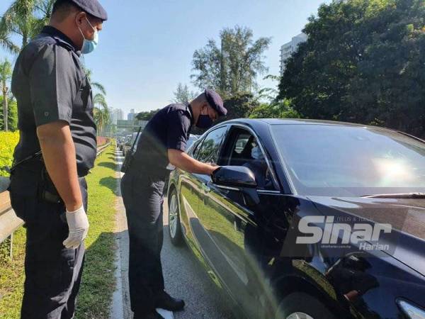 Soffian sedang memeriksa surat kebenaran merentas daerah daripada salah seorang pemandu di sekatan jalan raya di Lebuhraya Tun Dr Lim Chong Eu menghala ke Jambatan Pulau Pinang, pada Selasa.