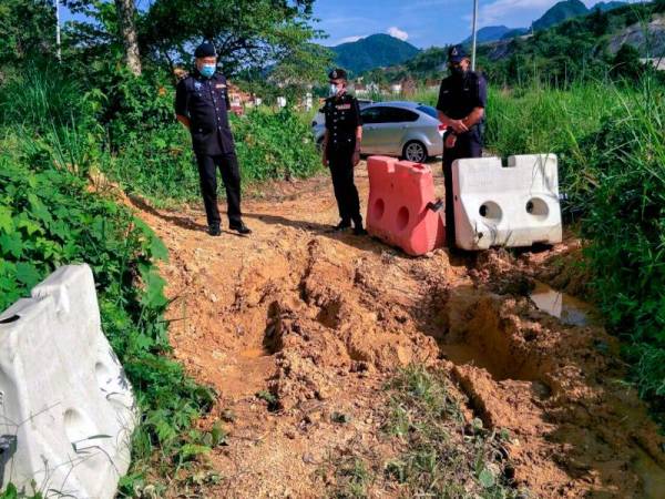 Ketua Polis Daerah Gua Musang, Superintendan Sik Choon Foo (kiri) bersama anggotanya meninjau lorong tikus yang ditimbus semula individu yang degil mahu merentas daerah di Kampung Tanah Puteh. - Foto Bernama
