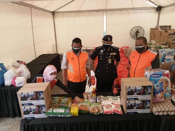 Che Samsuzuki (dua dari kiri) bersama Mohamed Mokhsein melihat persiapan barangan bantuan makanan dan keperluan asas yang akan diagihkan kepada penduduk yang memerlukan.