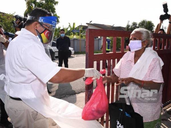 Amirudin menyampaikan sumbangan kepada salah seorang penduduk pada Program Agihan Bakul Makanan PKPS prihatin di Taman Pertama pada Rabu.