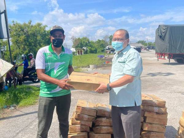 Ahmad Amzad (kanan) menyerahkan ikan kepada JPKK untuk dibungkus dan diagihkan kepada penduduk.