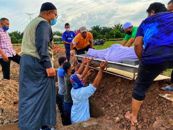 Mohd Shahrizan (kiri) menyempurnakan majlis pengebumian arwah Muhammad Afiq Hakimi di Tanah Perkuburan Batu Muda, Raudhatul Sakinah, Kuala Lumpur pada Jumaat.