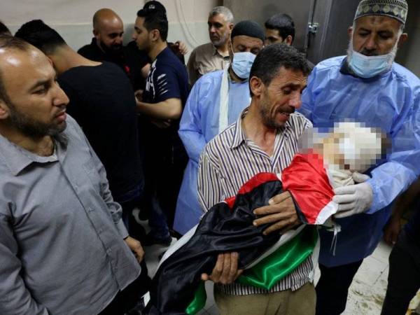 Seorang lelaki Palestin memeluk erat jenazah anak perempuannya yang berusia tujuh tahun selepas kediaman mereka di utara Genting Gaza dibedil jet Israel dalam serangan pada Mei lalu. - AFP
