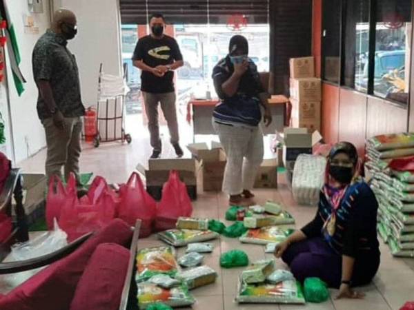 Aznel (kiri) bersama petugas di Pusat Khidmat DUN Pengkalan Hulu sedang menyediakan pek keperluan makanan untuk penduduk di kawasan PKPD yang akan diagihkan pada Isnin.